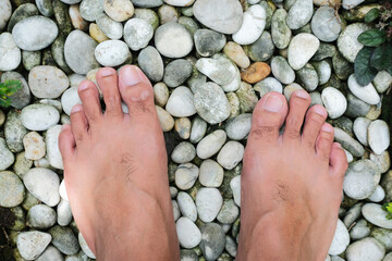 Barefoot guy walking above the white stones. Top view