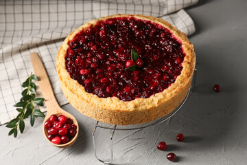 Metal stand with tasty lingonberry pie on light background