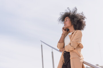 young black hispanic latina girl with afro and looking to the side worriedly leaning on a handrail