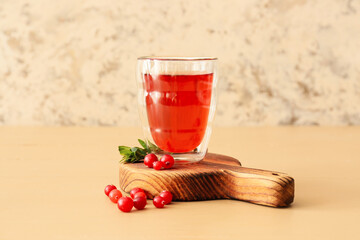 Glass of tasty lingonberry tea on table