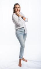 portrait of a woman in the studio. girl in a white shirt and blue jeans, barefoot. blonde with straight hair and bright makeup. isolated white background