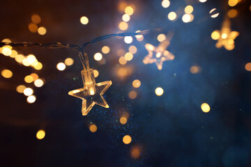 Christmas warm gold garland lights over dark background with glitter overlay