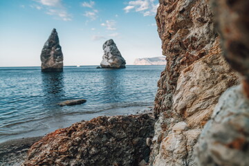 Peaceful seascape over the beach during sunset, with rocky volcanic cliff is lit by the warm sunset. Clear sky, no clouds. Nobody. Copy space. The concept of calmness silence and unity with nature.