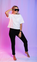 Fototapeta premium Woman in white t-shirt, black jeans and sunglasses on colorful background