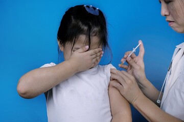 A cute young Asian girl terrified by injection at the hospital. Girl afraid of syringe needle...