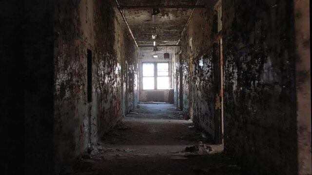 Scary hellish walk through decrepit abandoned sanitorium hallway, window's light pulses in an evil manner