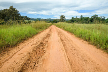 Fototapeta na wymiar View of dirt road in countryside with blue sky