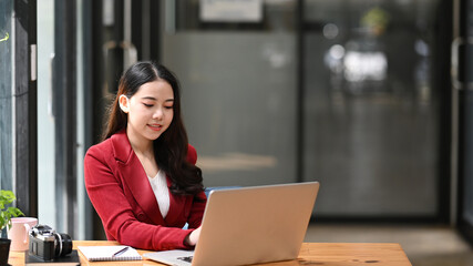 Confident businesswoman using laptop computer at office desk.