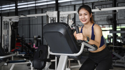 Obraz na płótnie Canvas Smiling fit young woman cycling machines in sports club.