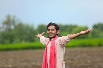 Young indian farmer spreading hand at agriculture field.