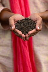 Indian farmer holding black soil in hand.