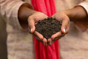 Indian farmer holding black soil in hand.