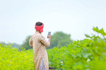 Indian farmer using smartphone at agriculture field.