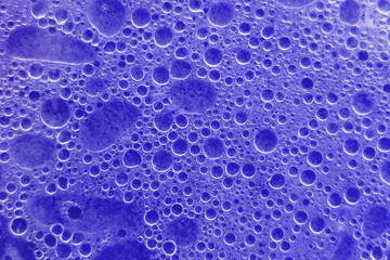 Air bubbles on the surface of the water. Fat rings in an aqueus emulsion. Blue liquid with bubbles. Water surface texture. horizontal image