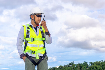 engineer wearing safety harness use using walkie-talkie while working on roof top
