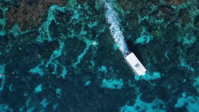 Unique view of a dive boat as it moves through the water over a tropical reef system. High drone view
