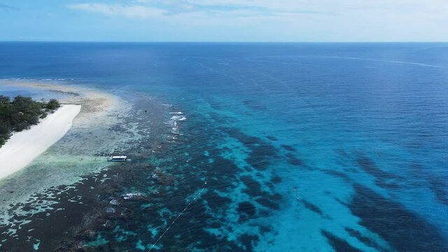 High view across a underwater reef system towards a group of boats moored in the tropical blue Island waters.
