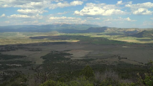 Time lapse of the Mancos river valley showing clouds and shadows moving, beautiful farm land, highway 160, and the San Juan Mountains in the distance.