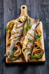 Roasted sea bass on a black wooden table, close-up