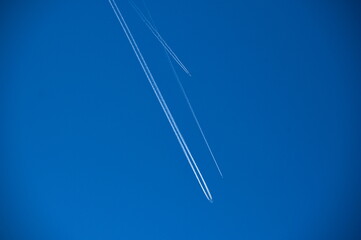 Low angle view of airplane tracks against clear blue sky