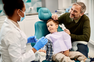 Happy father and his son talk to dentist during appointment at dental clinic.