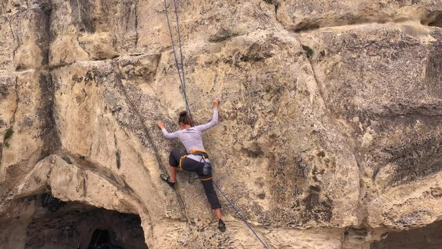 Outdoors rock climbing. Woman confidently rock climbs mountain, fitness lifestyle. Climbing extreme active sport activity. Aerial view mountains