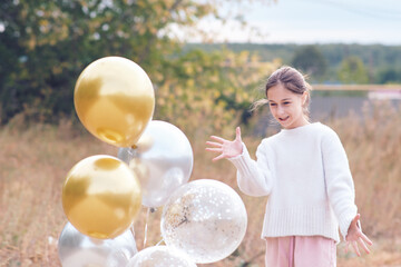 Happy teenage girl in white sweater mentally controls gel balloons.