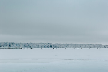 Fototapeta na wymiar Winter seashore with people in freezing day. Fishers on ice in sea.