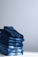 a pile of blue jeans on a light background. Close up. Copy space. Sunlight