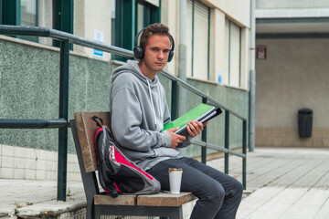 student with headphones drinking takeaway drink in college or university