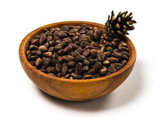 Pine nuts and cone in the bowl isolated on white background. Cedar unpeeled nuts and cone.