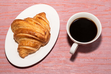 Breakfast food croissant in plate and coffee on wood table.