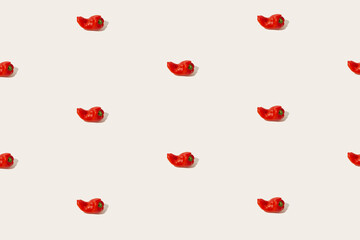 Aesthetic vegetable food pattern made of red sweet peppers isolated on the pastel beige background. Sun and shadows. Source of vitamin C and vegan kitchen ingredient idea. Minimalist texture concept.