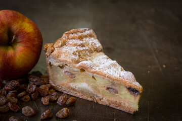 Piece of Dutch Apple pie with raisins photographed on an old baking tray. 