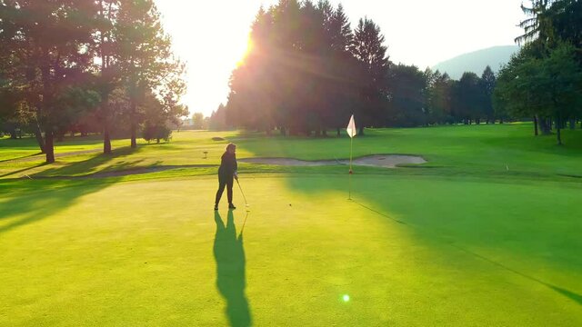 Golfer Putting the Golf Ball on Putting Green in Sunset with Shadow in Switzerland.