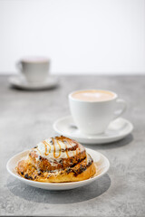 Cappuccino and rolled bun with caramel