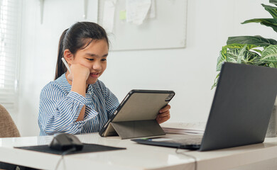 Asian  girl children using laptop computer tablet , studying through online e-learning system. New normal.Covid-19 coronavirus.Social distancing.stay home
