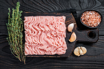 Fresh Raw mince or ground chicken meat on wooden chopping board with thyme. Black wooden...