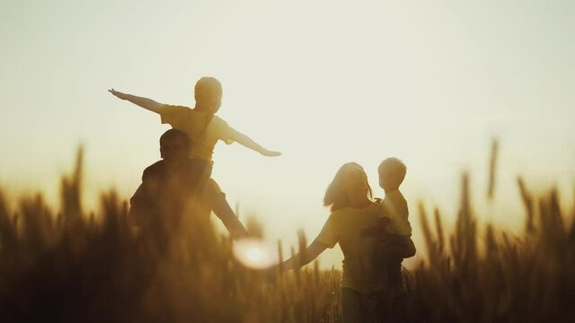 happy family in the agricultural park. silhouette of a friendly family of farmers walking in a wheat field. agriculture kid dream concept. silhouette family walking sunset in the wheat field in park