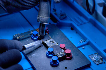 Hands in gloves of cellphone technology device maintenance engineer work on removing microprocessor...