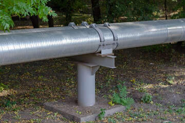Piping on metal supports in the woods or park. Two pipes covered