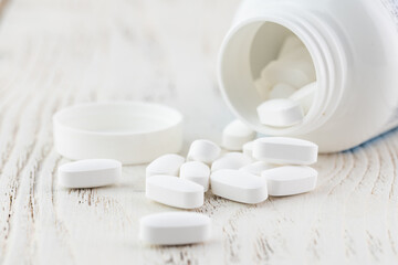 Fototapeta na wymiar White empty medical jar,scattered tablets in capsules
