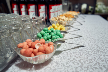 Obraz na płótnie Canvas Multi-colored salted nuts in plates on a buffet table along with glasses and drinks