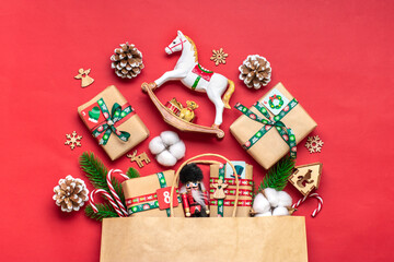 Handmade wrapped red, green gift boxes decorated with ribbons, snowflakes and numbers, Christmas decorations and decor in bag on red table Xmas advent calendar concept Top view Flat lay Holiday card