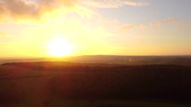 Cinematic aerial sunset over the green hills of the South Downs Way, England