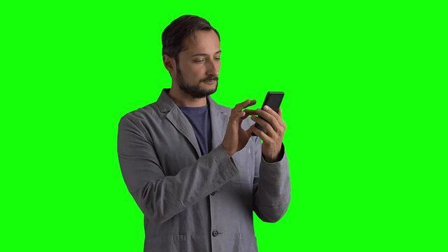 A man in a suit uses a mobile phone against a green screen. Chromakey slow motion. Composition in the torso
