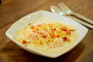 Creamy spaghetti carbonara on a plate at the main court table in this delicious and popular Italian restaurant.