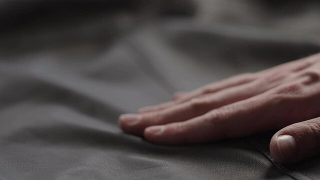 Slow motion shot man touching fine leather closeup