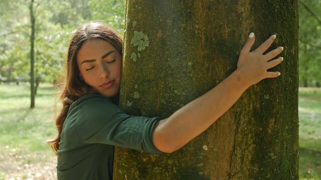 Woman hugging tree trunk in park