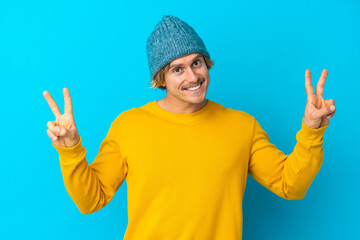 Naklejka premium Handsome blonde man isolated on blue background showing victory sign with both hands